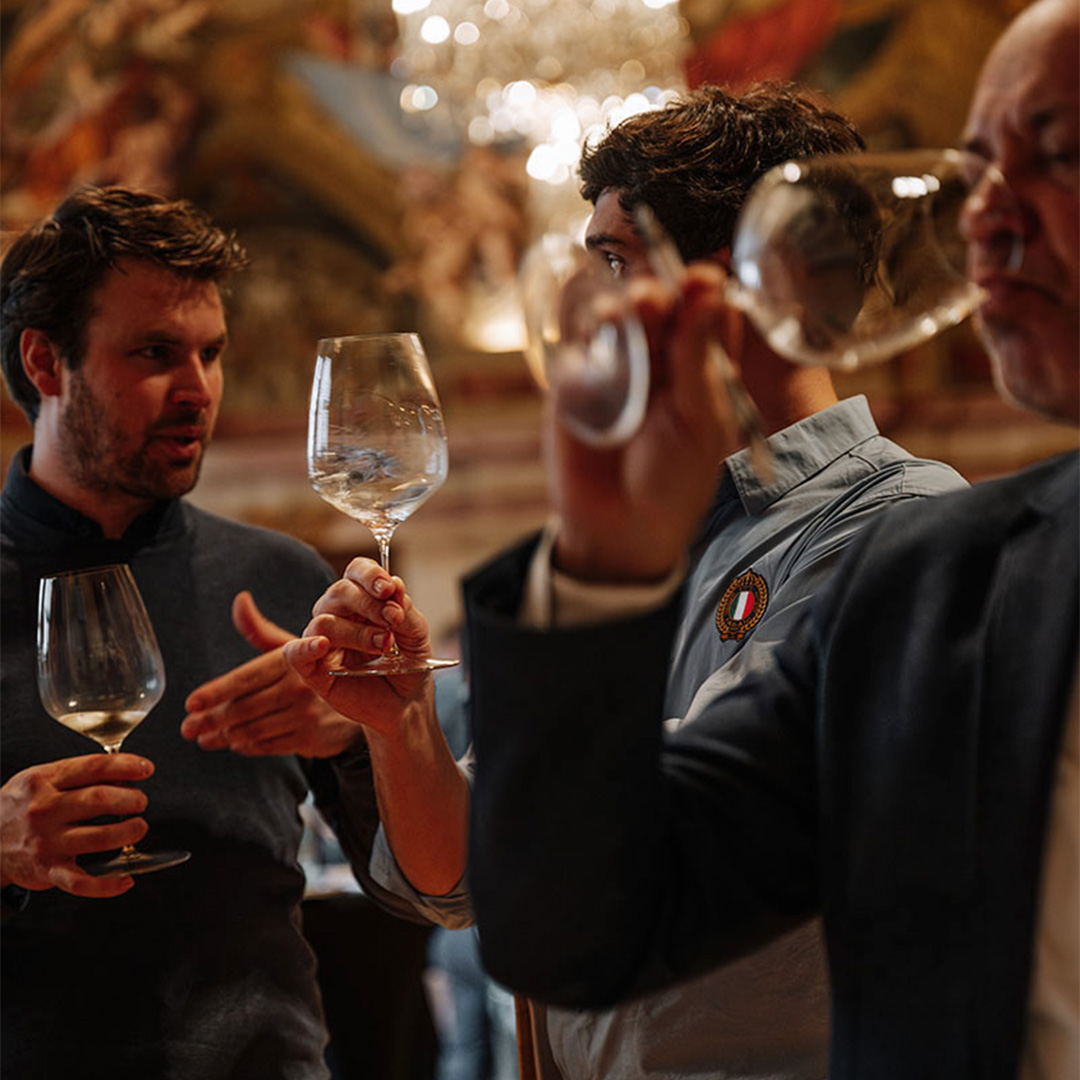 Portfolio Tasting 2024 Drei Besucher des Portfoliotastings verkosten Wein und unterhalten sich darüber