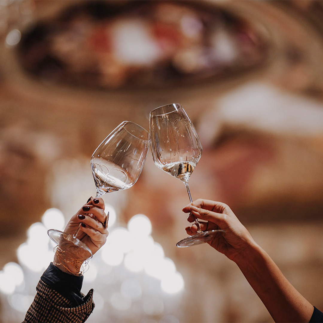 Portfolio Tasting 2024 Zwei Weingläser, mit denen angestoßen wird.